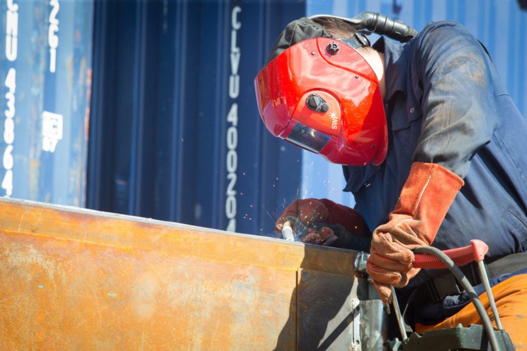 Workman welding a shipping container