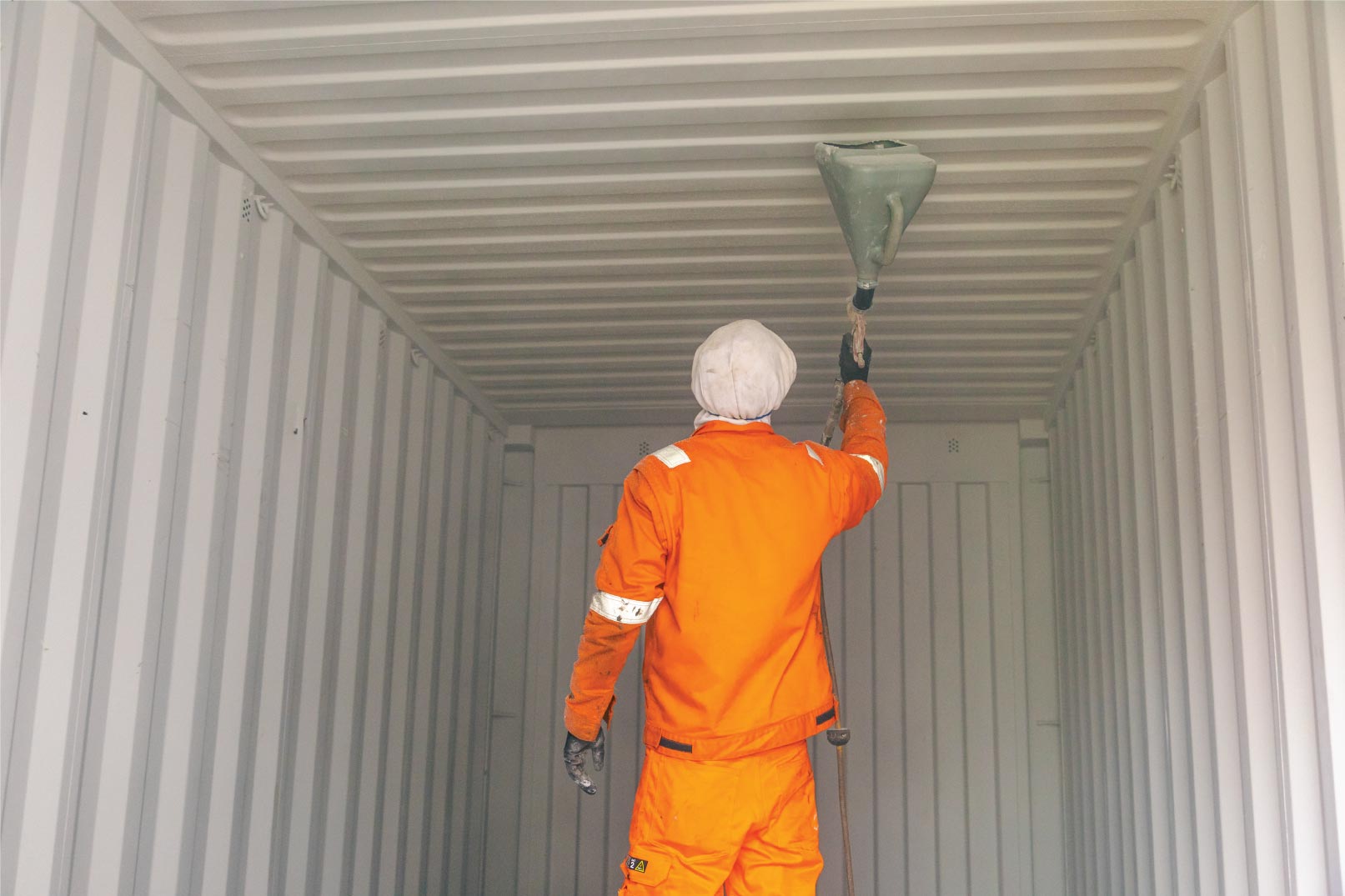 Painter using grafo-therm paint for container interior
