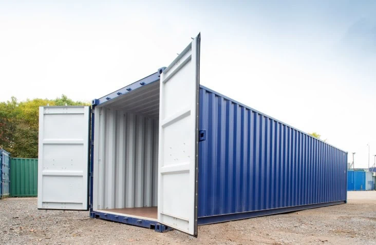 Blue 40ft shipping container with both doors open, showing white interior walls and plywood floor, photographed outdoors on a container yard