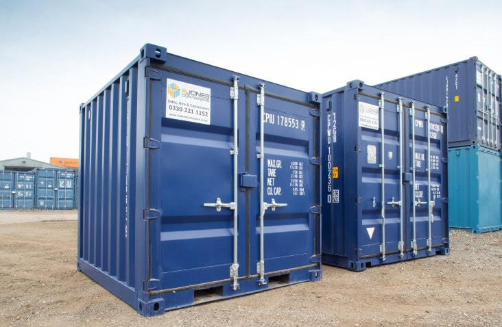 Two 10ft blue shipping containers positioned side by side, one standard height and one high cube, both with closed double doors and visible company branding