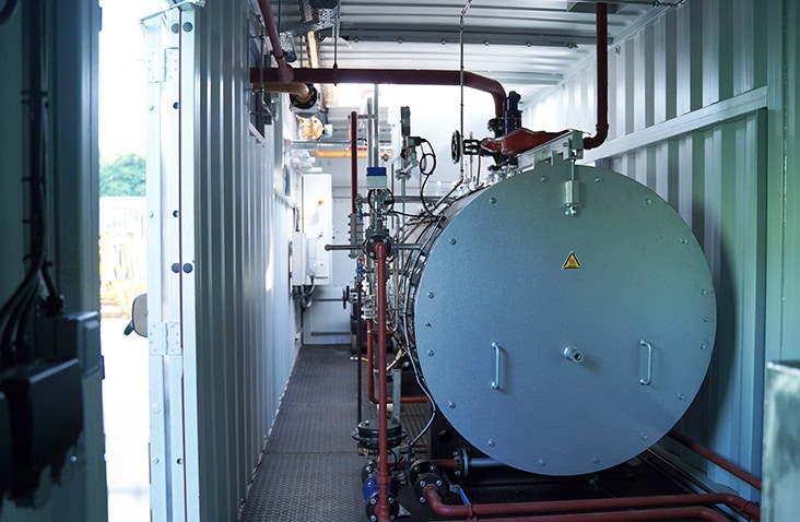 A shipping container converted into a boiler room, showcasing the durable and secure solutions containers provide for a range of boiler types, including biomass and steam.