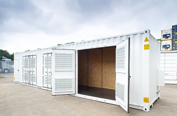 Red 40ft shipping container modified into six separate storage units, each with an individual personnel door.