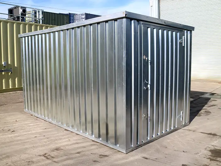 A galvanised flat pack metal storage unit assembled outdoors on concrete, with corrugated steel panels and a secure door.