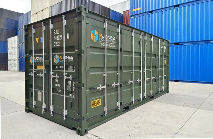 Green 20ft side opening shipping container with double cargo doors and full-length side access, branded with S Jones Containers logo, positioned in a storage yard with stacked blue containers in the background