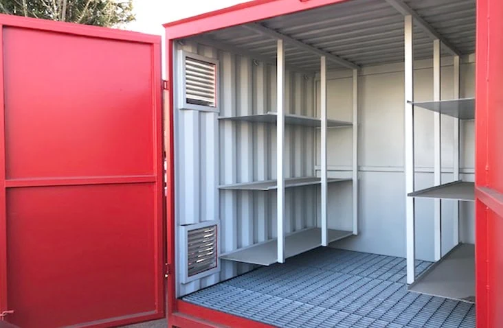 Inside a red shipping container fitted with durable built-in metal shelving and wall vents, designed for organised storage. 