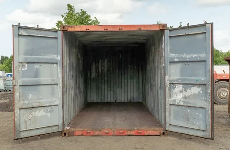 Used red 20ft shipping container with both cargo doors open, showing a dry interior suitable for storage or site use, with visible wear consistent with second-hand condition. 
