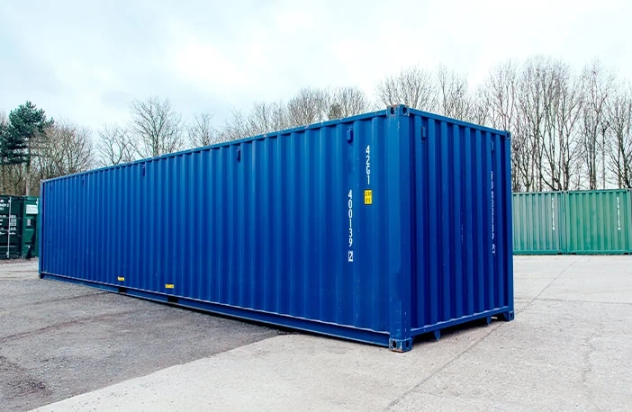 Side profile of a blue 30ft container on hardstanding, long corrugated wall with lifting points and identification marks
