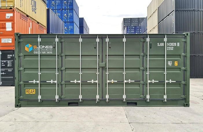 Front view of a green 20ft side opening shipping container with side doors closed, featuring S Jones Containers branding and yellow “REAR” marking, positioned in a container yard surrounded by stacked units