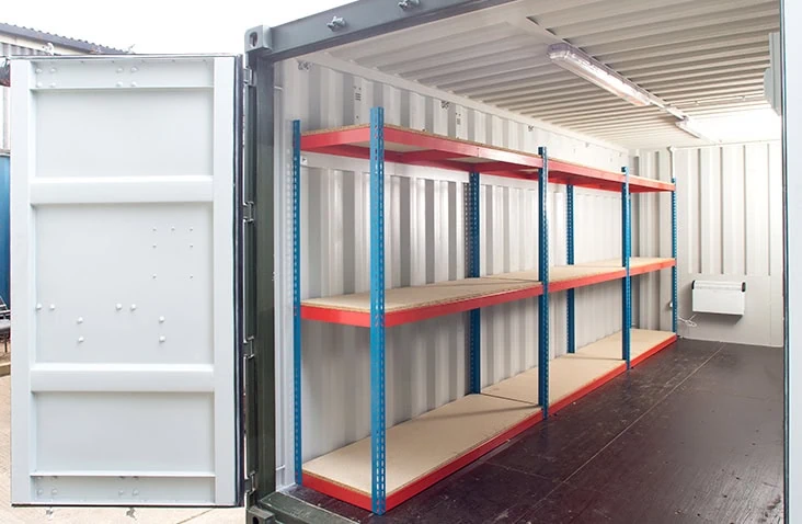 Interior of a shipping container fitted with self-assembly boltless shelving units along one wall for organised storage. 
