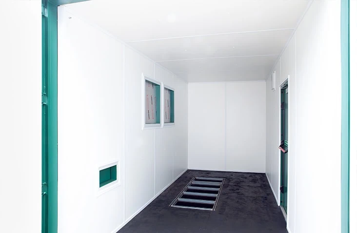 Clean white-lined insulated shipping container interior with built-in floor drainage and ventilation panels.