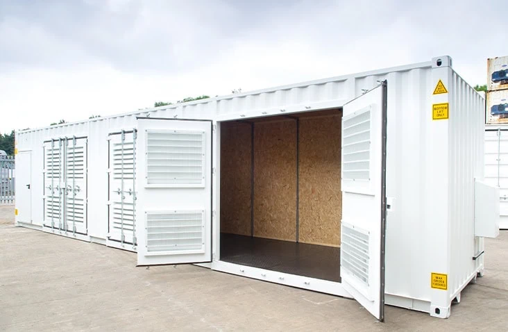 40ft white shipping container converted into a ventilated industrial enclosure with louvred doors and OSB-lined interior, designed to house compressors or plant equipment.