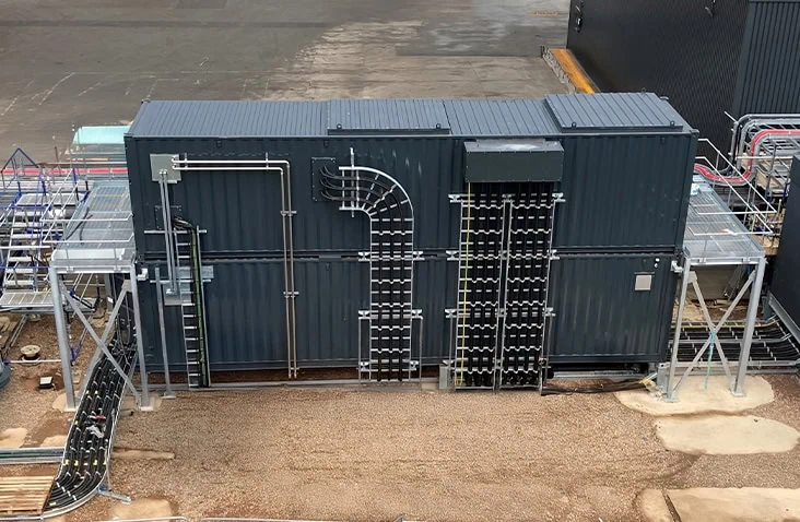 Energy regeneration container enclosure with external cable management, showing a containerised plant room fitted with pipework, electrical cabling, access platforms and structural supports for energy recovery and power system integration.