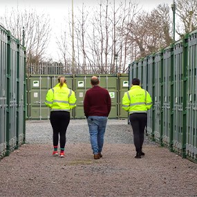 Customers walking through a secure self storage facility made from individual green shipping container units, offering external-access container storage solutions.