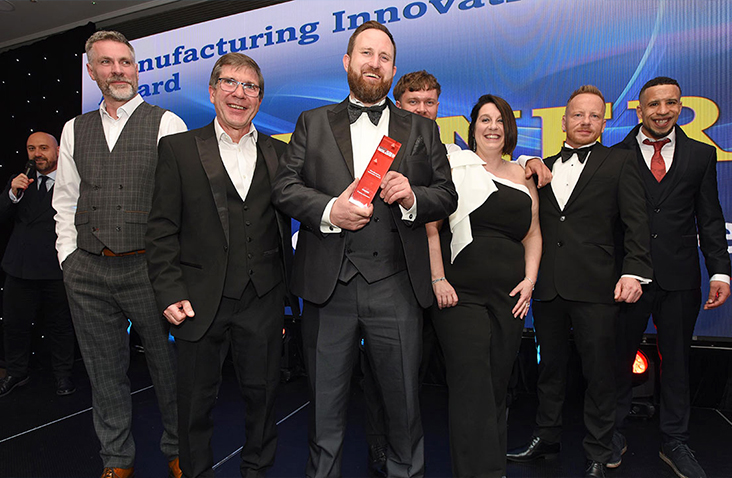 S Jones Containers conversion team celebrating on stage after winning the Manufacturing Innovation Award at the Made in the Midlands Awards 2025. The team members are dressed in formal attire holding the trophy at an industry awards event.