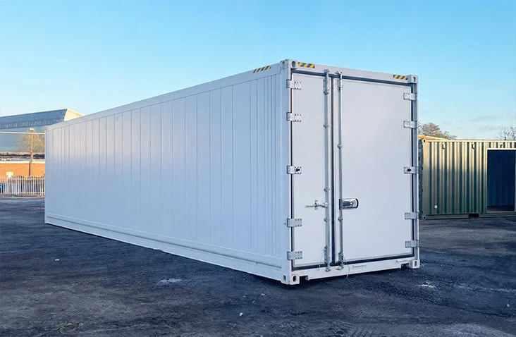 White 40ft refrigerated shipping container (reefer) viewed from the front corner in a container depot, showing the double cargo doors and insulated construction. Designed for temperature-controlled storage and transport between -25°C and +25°C, this 40ft reefer shipping container is available to hire from S Jones Containers with a minimum hire period of 90 days.