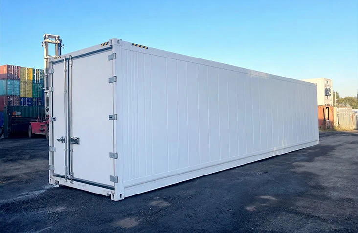 Long side view of a white 40ft refrigerated shipping container (reefer) with insulated panels and double cargo doors, positioned in a container depot. Suitable for temperature-controlled storage from -25°C to +25°C, this 40ft reefer is available to hire from S Jones Containers with a minimum 90-day hire period.
