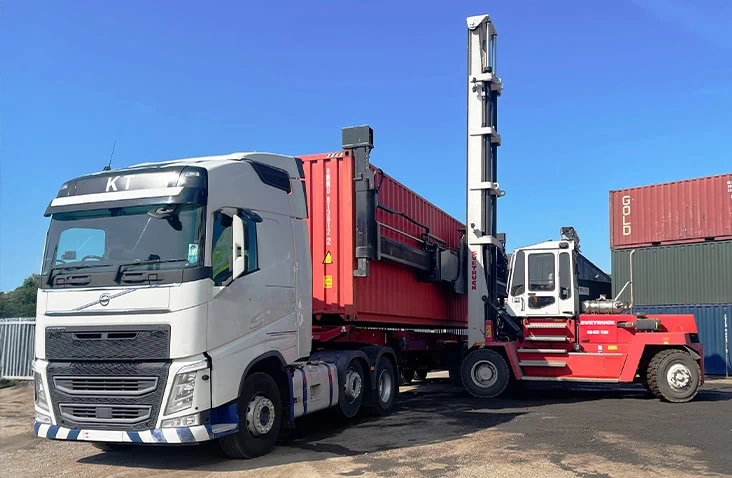 New Svetruck empty container handler loading a red shipping container onto a lorry at the S Jones Containers depot, demonstrating efficient container handling, loading, and logistics operations for nationwide container sales and hire.
