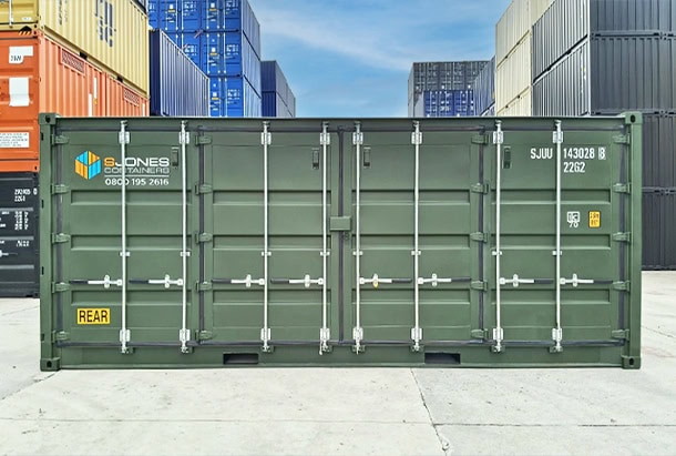 Full side view of a green side-opening shipping container supplied by S Jones Containers, featuring multiple full-height hinged steel doors along the container's length, galvanised locking bars, secure locking mechanisms and a central lockbox. The container displays S Jones Containers branding and SJUU identification markings and is photographed at a container depot surrounded by stacked shipping containers. The side-opening design provides convenient access to stored goods, equipment and bulky items without relying solely on end-door access.